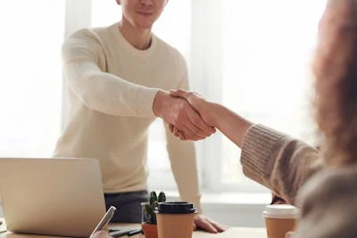 Handshake boven projectdocumenten tijdens een partnerschapsbijeenkomst